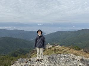 美ヶ原王が頭に立つ宮下さん。背景は松本平。